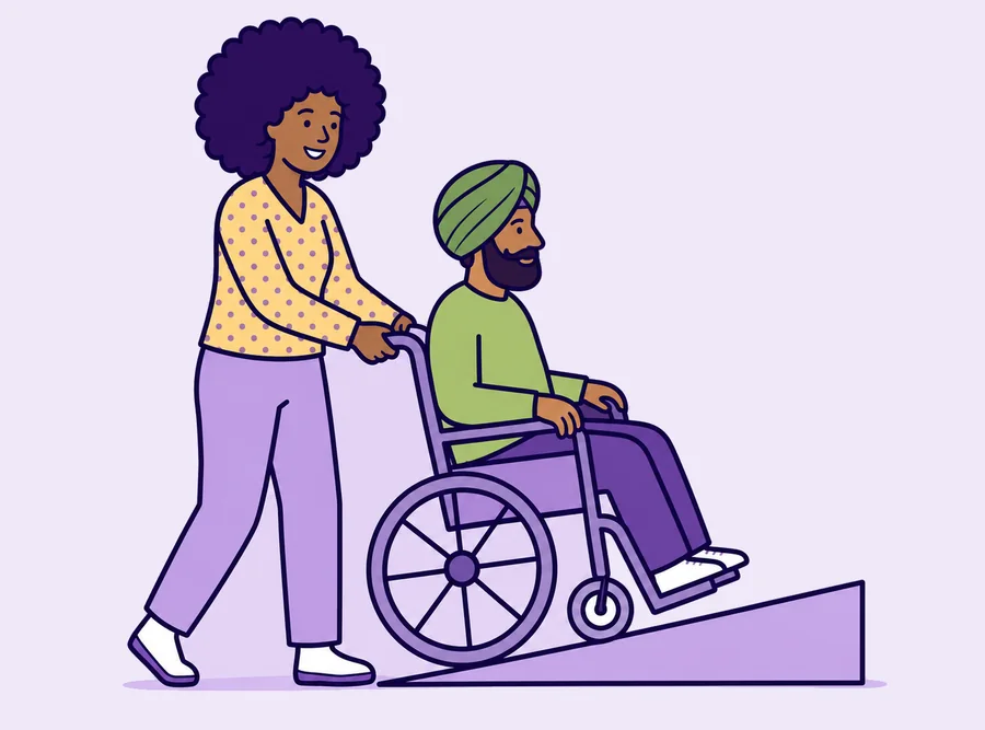A worker walking beside a man in a wheelchair as he comes up a ramp.