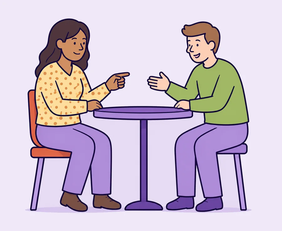 Two people sitting at a table, talking to each other.